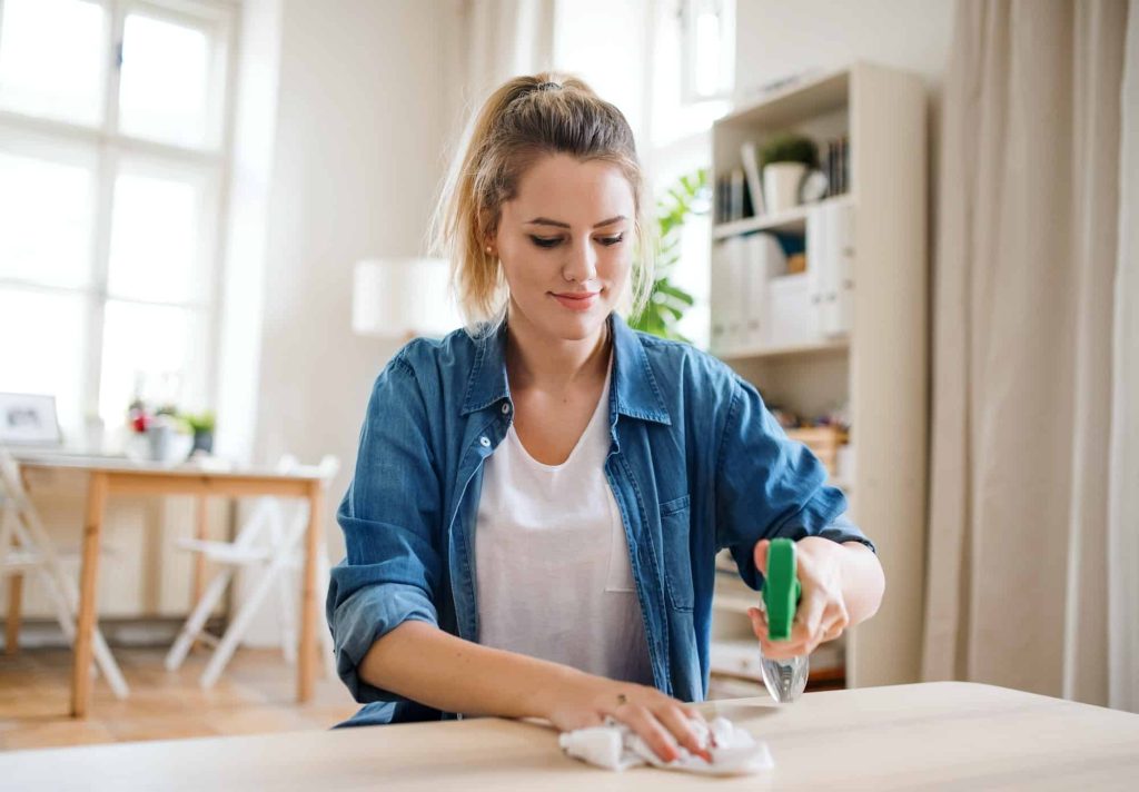 Young Women indoors at Home Cleaning Table.