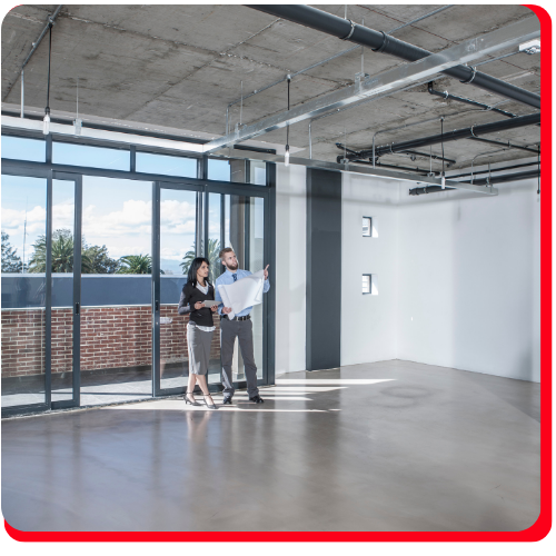 Two professionals review blueprints inside a bright commercial space with a polished epoxy floor.