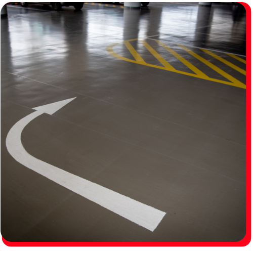 Epoxy-coated commercial parking floor with white arrow and yellow safety striping.