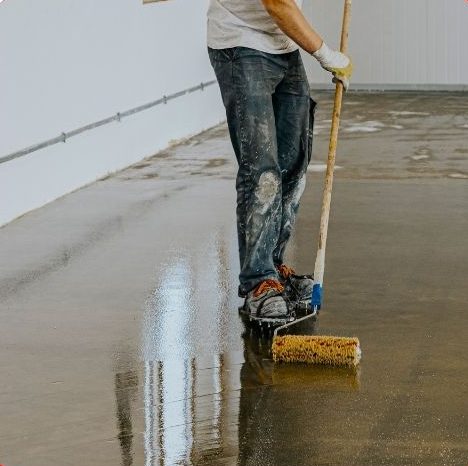 Worker applying epoxy coating to an industrial concrete floor in Aurora, Ontario.