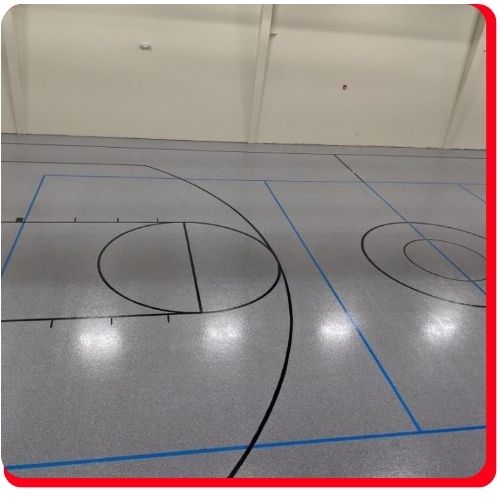 Indoor epoxy sports flooring with black and blue basketball court lines in Cambridge.