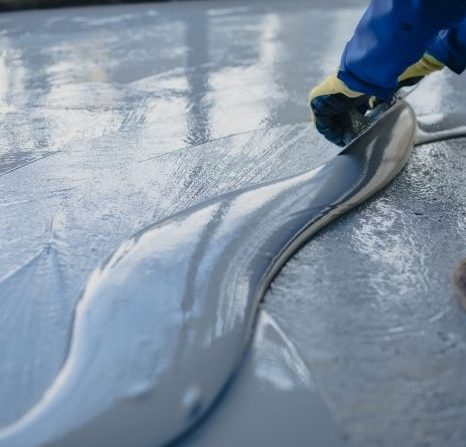 Worker spreading freshly poured epoxy coating on a concrete floor in Hamilton, Ontario.
