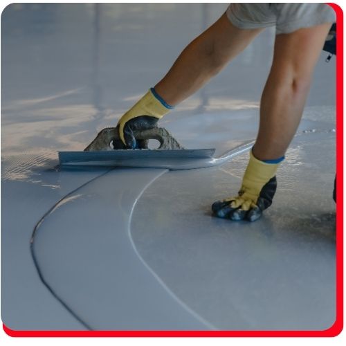 Contractor in Hamilton expertly smooths freshly poured epoxy flooring with a hand trowel.