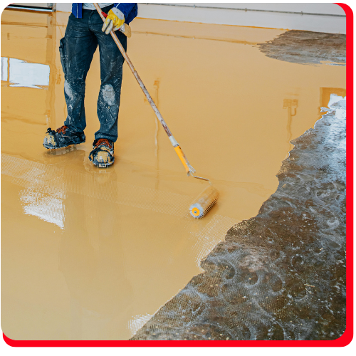 Worker applying yellow epoxy flooring with a roller over a prepped concrete surface in Markham.