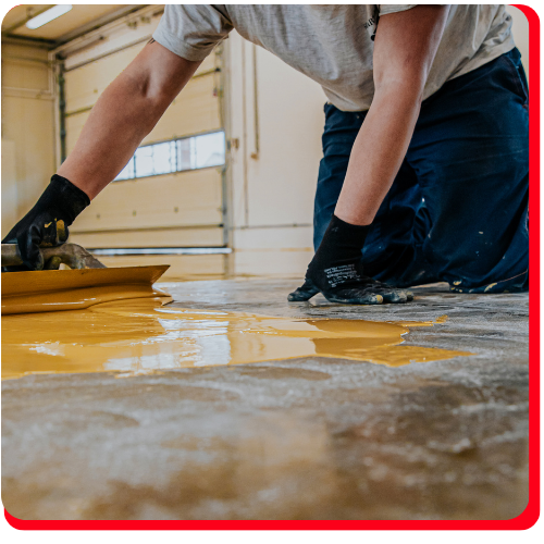 Worker applying yellow epoxy coating with a trowel on a concrete garage floor in Markham.