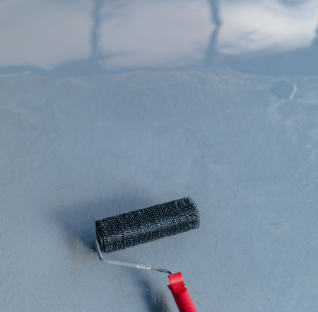 Close-up of a red-handled roller on a freshly applied grey epoxy floor in Mississauga.
