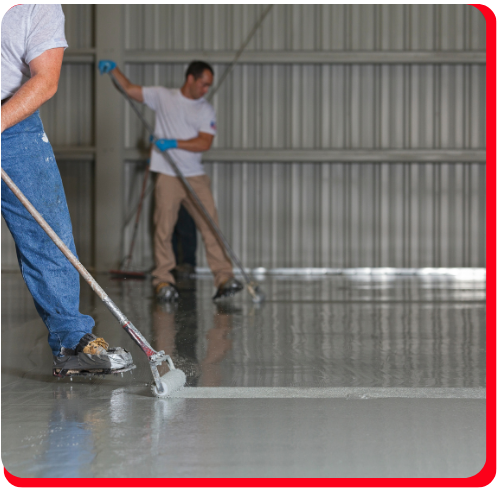 Two workers applying gray epoxy flooring in an industrial Mississauga warehouse.