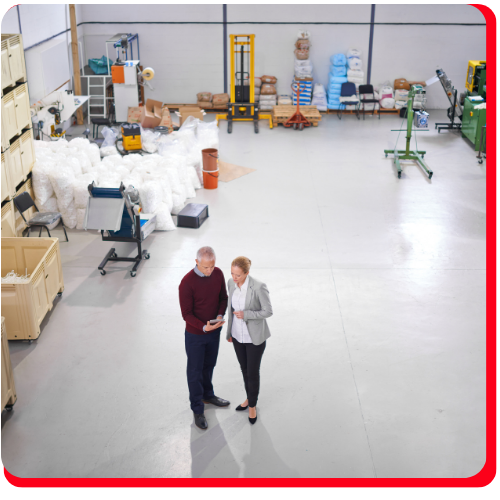 Clean industrial warehouse in Hamilton featuring seamless waterproof floor coating with two people inspecting the space.