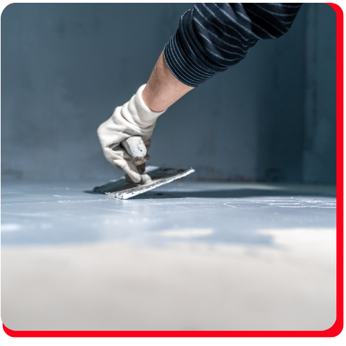 Close-up of a worker troweling waterproof floor coating in a Toronto building.