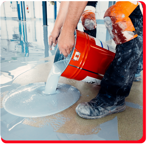 Worker pouring waterproof epoxy coating from a red bucket onto an indoor floor in Toronto.