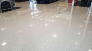Close up of a polished light colored epoxy floor in a car showroom with vehicle reflections