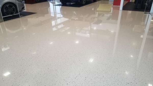 Close up of a polished light colored epoxy floor in a car showroom with vehicle reflections