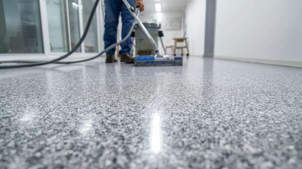 Technician polishing a speckled epoxy floor during installation in a commercial hallway