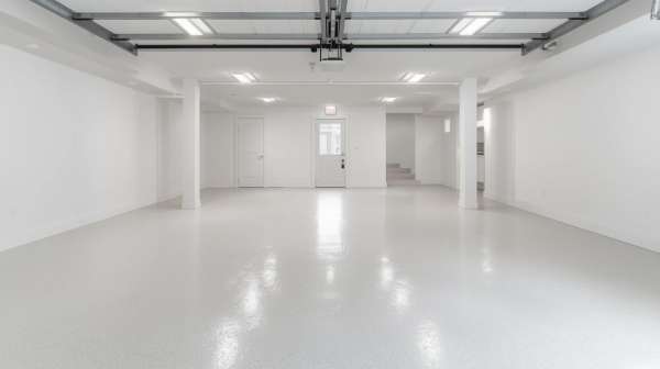 Large modern garage with smooth light gray epoxy floor and bright overhead lighting