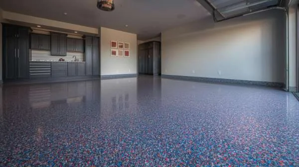 Spacious finished garage with dark cabinets, wall art, and a glossy multicolor flake epoxy floor.